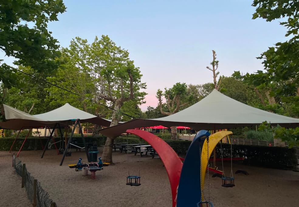 Stretchtent boven speeltuin in avondlicht