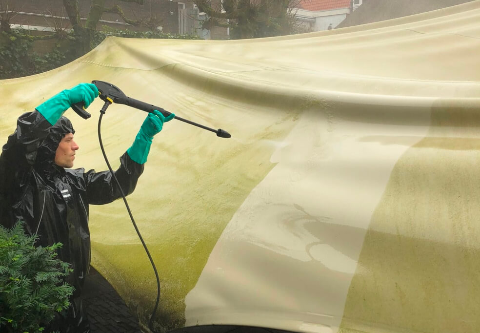 Teamlid reinigt stretchtent met hogedrukspuit